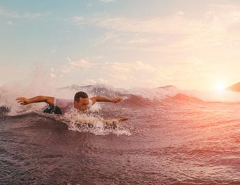 Guy paddling out into the waves on a longboard