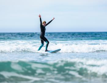 Woman on surf board with her hands up 