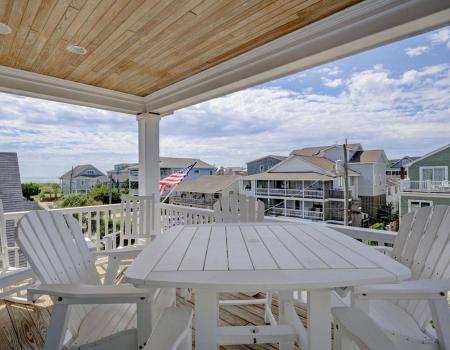 A white deck table and chairs sit on the balcony at Casa Crane, a vacation rental in Wrightsville Beach, N.C.