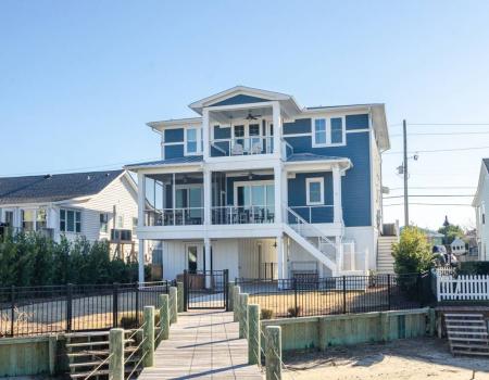 A view of the exterior of Hooks Cottage from its private dock. The five-bedroom, three-story blue vacation rental sits along the Intracoastal Waterway in Wrightsville Beach.