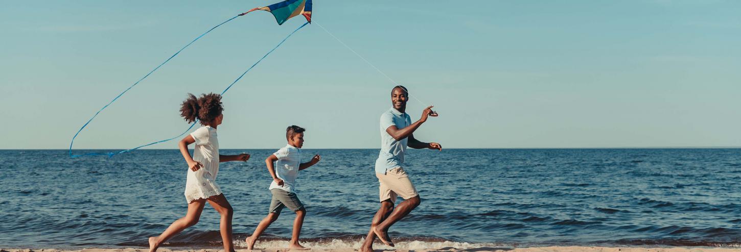 Family Running on Beach with Kite