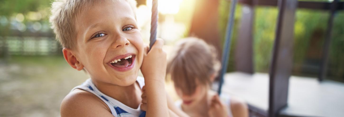 Boy smiling on rope swing outside