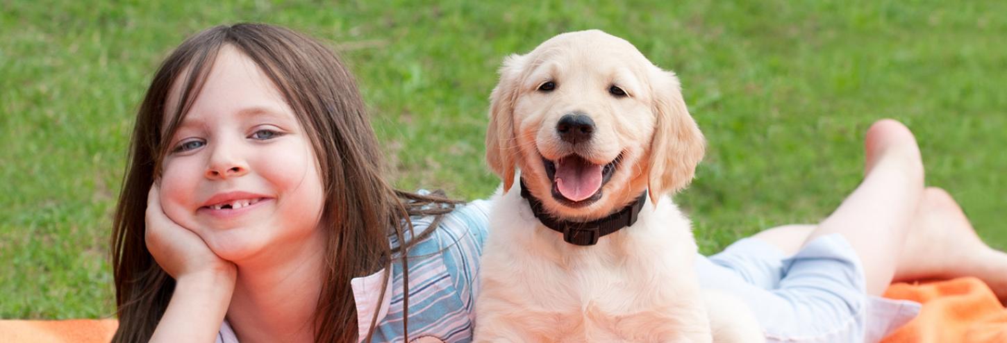 Young girl laying down with her puppy at the park