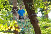 Teen walking on a rope line in the trees