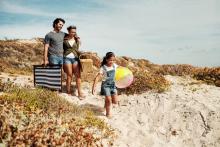 family beach vacation, little girl carrying beach ball, father carrying picnic basket to beach