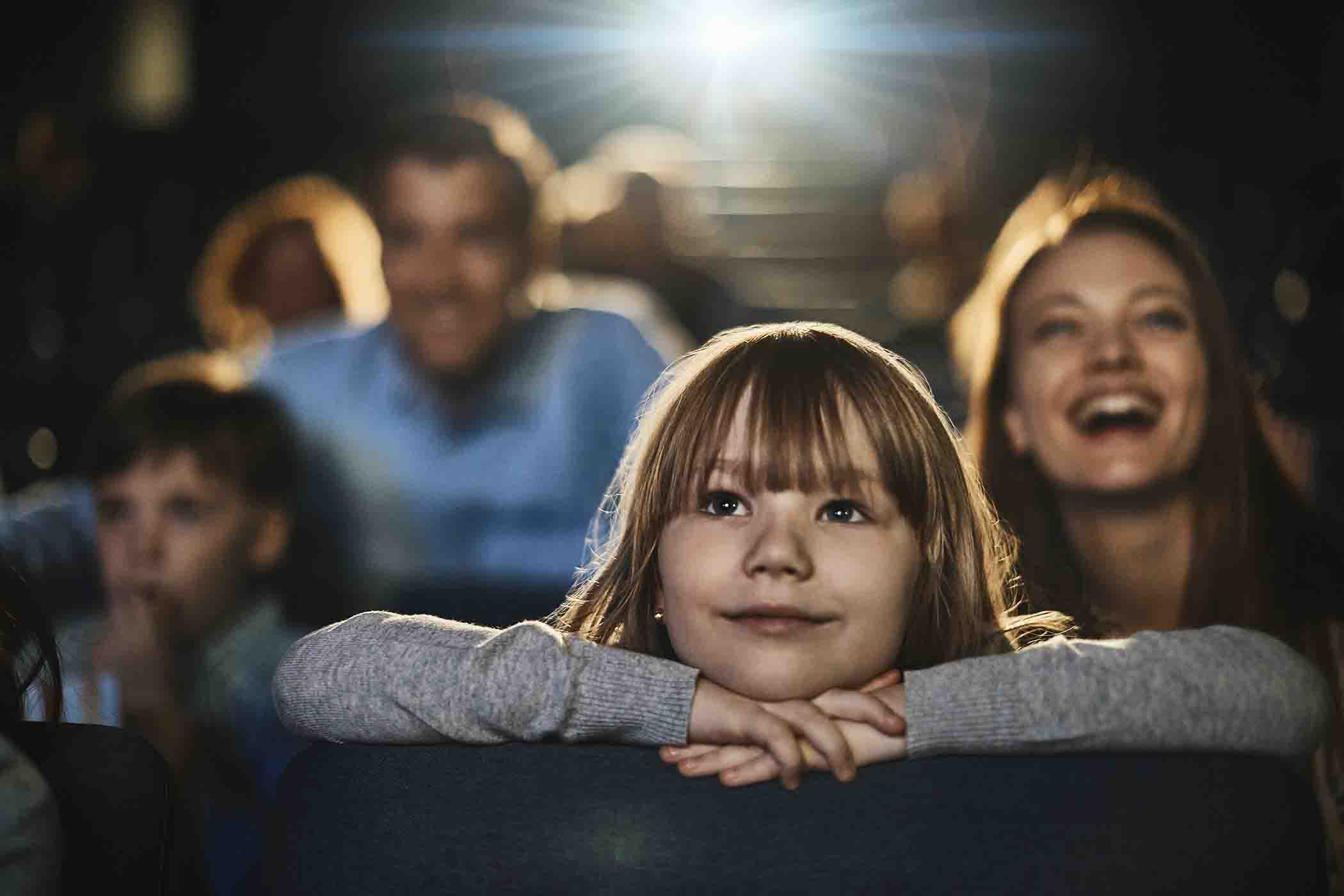 Young girl enjoying a movie at the theatre with her parents