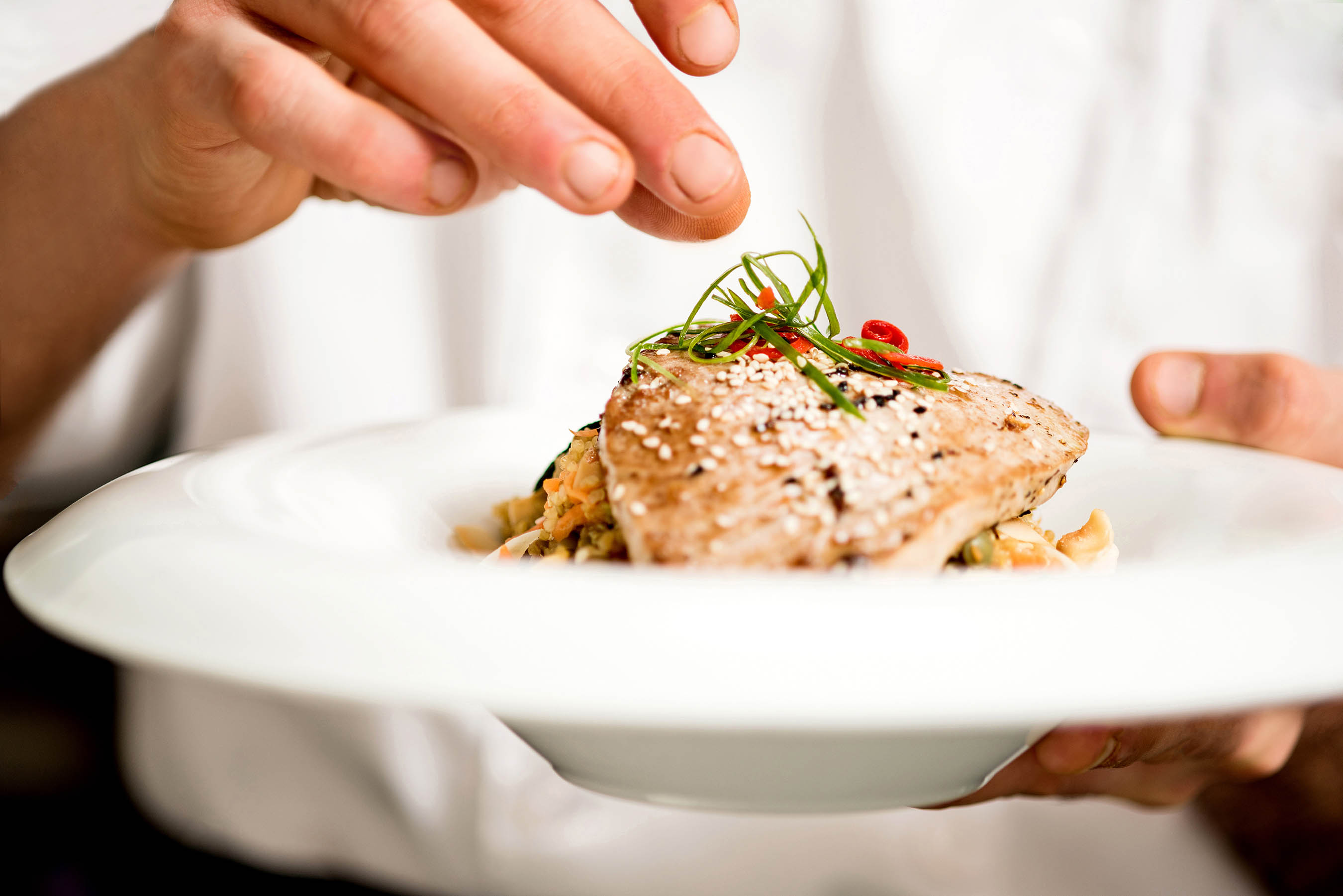 Chef Sprinkles Topping on a Chicken Dish